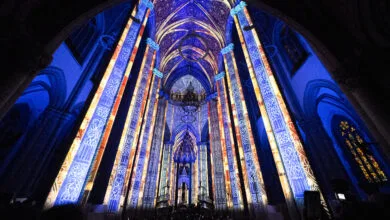 Interior da Catedral da Sé iluminado por projeções em tons de azul e dourado que cobrem colunas e abóbadas góticas durante o espetáculo LuminiScence.