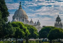 Vista panorâmica de Calcutá, capital do estado de Bengala Ocidental, com edifício histórico e áreas verdes em primeiro plano.