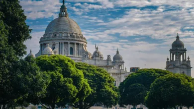 Vista panorâmica de Calcutá, capital do estado de Bengala Ocidental, com edifício histórico e áreas verdes em primeiro plano.