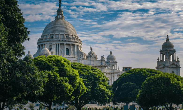 Vista panorâmica de Calcutá, capital do estado de Bengala Ocidental, com edifício histórico e áreas verdes em primeiro plano.