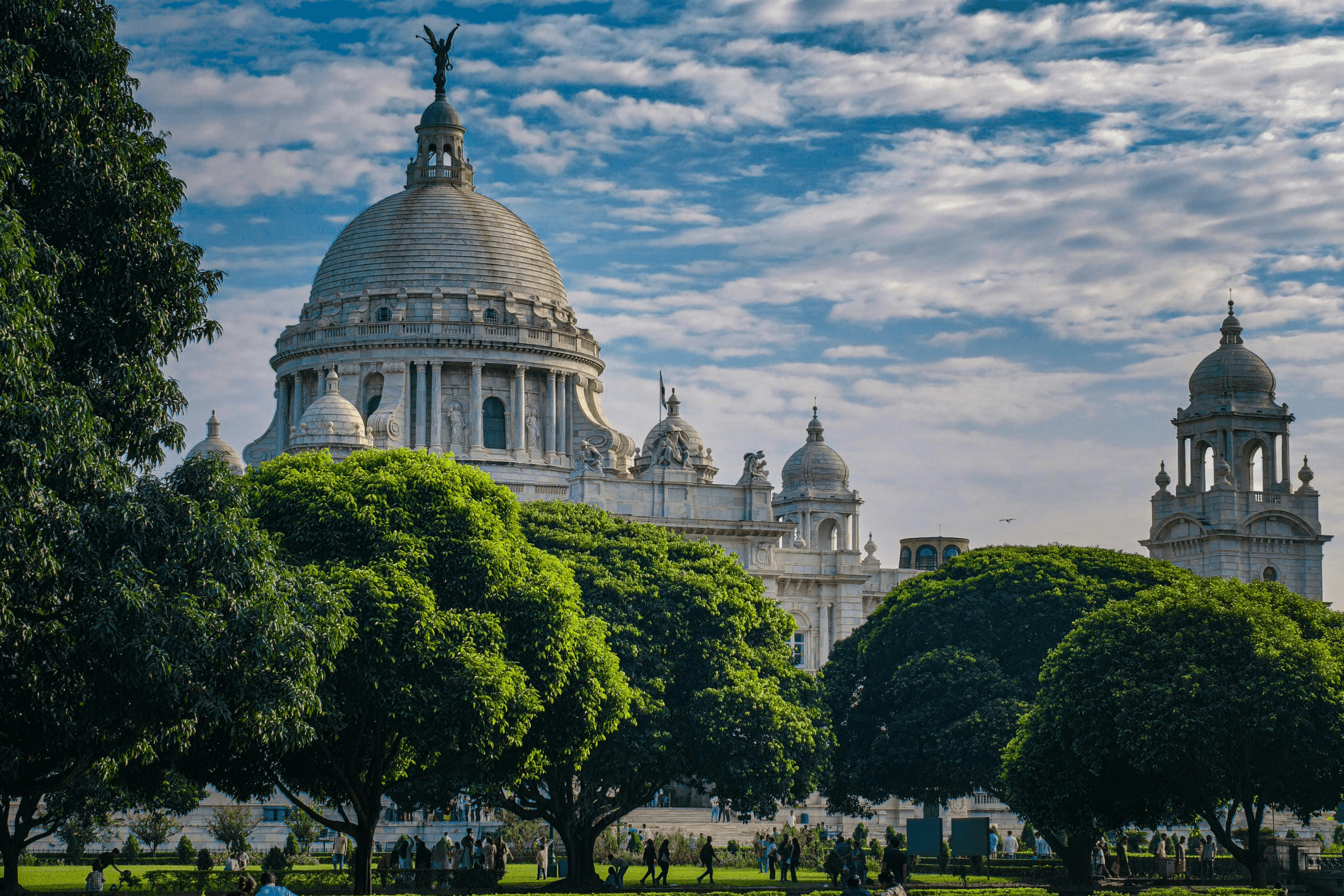 Vista panorâmica de Calcutá, capital do estado de Bengala Ocidental, com edifício histórico e áreas verdes em primeiro plano.