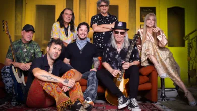 Integrantes da banda Tutti Frutti posam juntos em estúdio, alguns sentados e outros em pé, com instrumentos musicais.