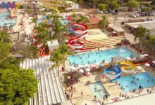Vista aérea do parque aquático da Pousada Maeda com piscinas repletas de banhistas e diversos toboáguas coloridos em espiral.