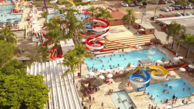 Vista aérea do parque aquático da Pousada Maeda com piscinas repletas de banhistas e diversos toboáguas coloridos em espiral.