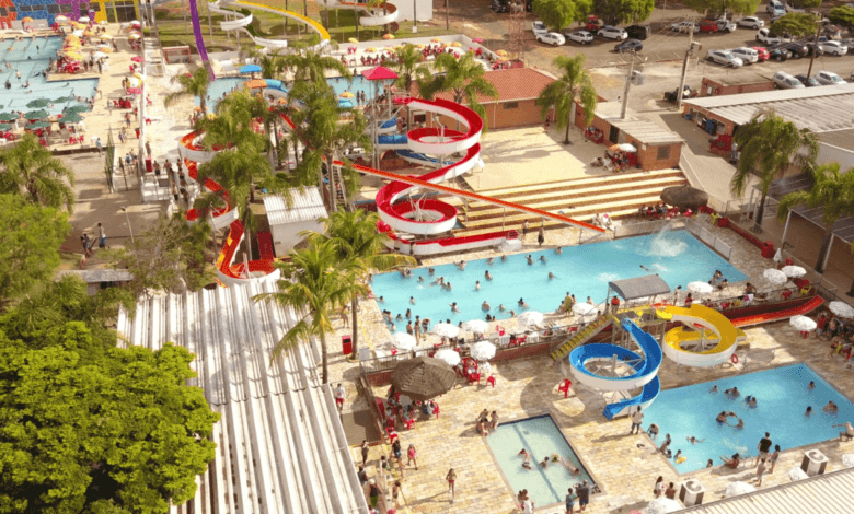 Vista aérea do parque aquático da Pousada Maeda com piscinas repletas de banhistas e diversos toboáguas coloridos em espiral.