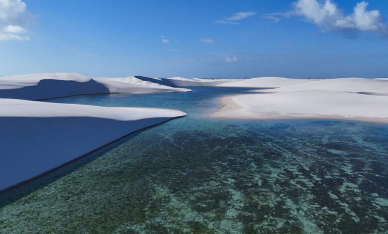 Lagoa de águas cristalinas entre dunas de areia branca nos Lençóis Maranhenses