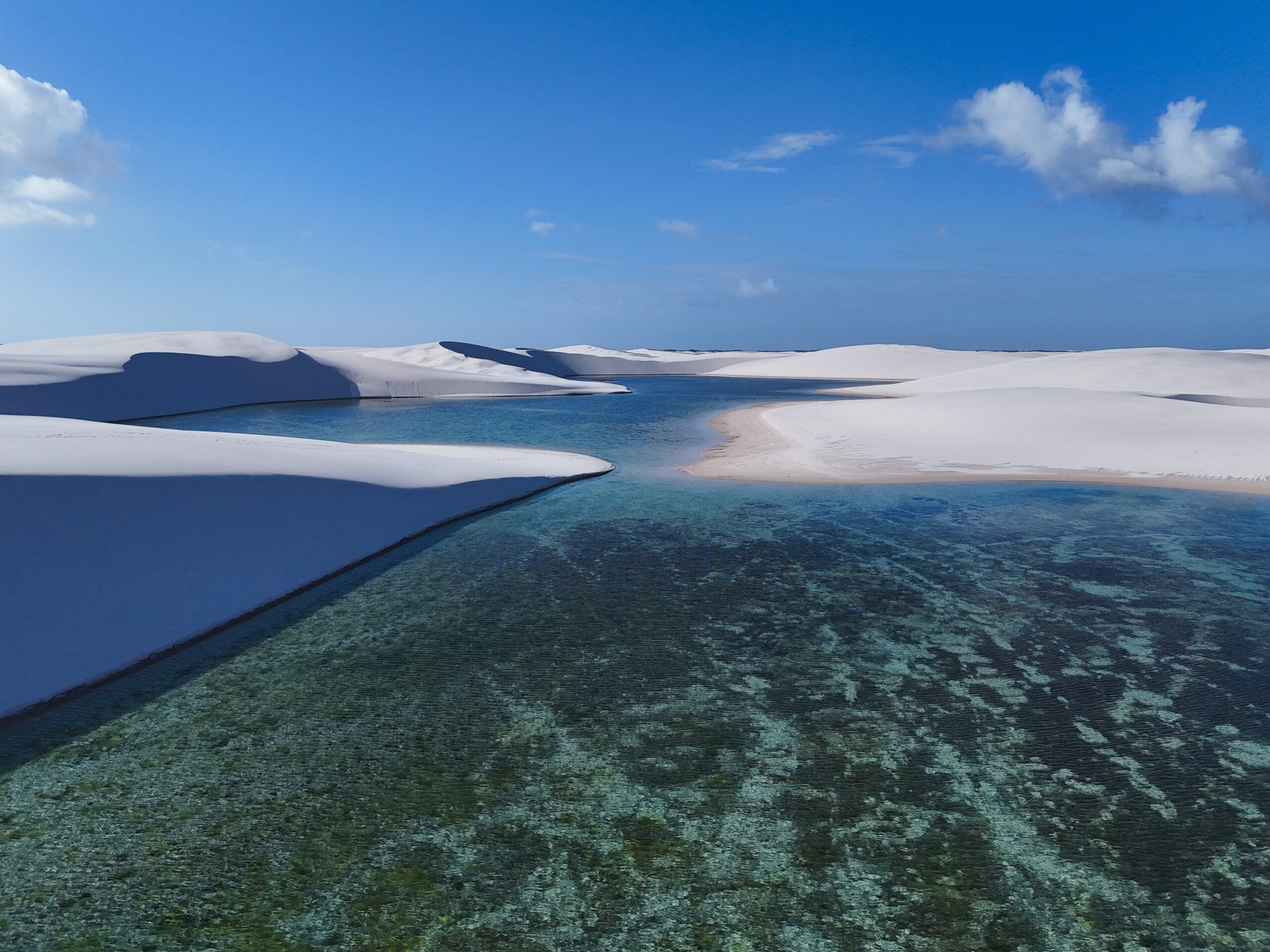Lagoa de águas cristalinas entre dunas de areia branca nos Lençóis Maranhenses