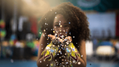 Foliã jogando confete durante celebração de Carnaval em ambiente colorido