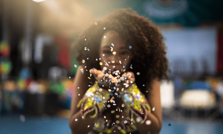 Foliã jogando confete durante celebração de Carnaval em ambiente colorido