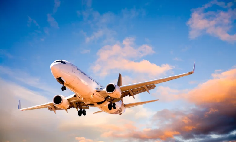 Avião comercial branco decolando com céu azul e nuvens ao fundo, representando voos para a Copa 2026