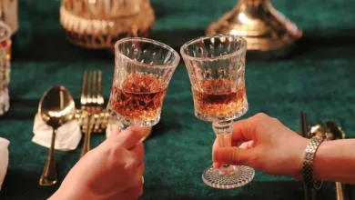 Close de duas pessoas brindando com taças em uma mesa de restaurante elegante com iluminação quente.