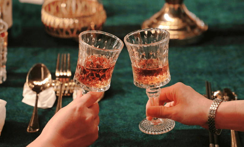 Close de duas pessoas brindando com taças em uma mesa de restaurante elegante com iluminação quente.