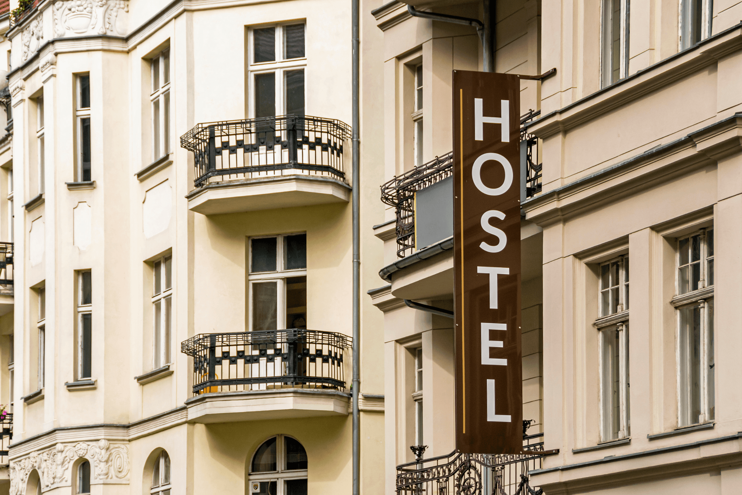 Fachada de prédio clássico europeu com uma placa vertical marrom onde se lê