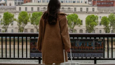 Mulher de costas segurando uma mala de viagem diante de uma paisagem urbana com rio, simbolizando liberdade e descanso.