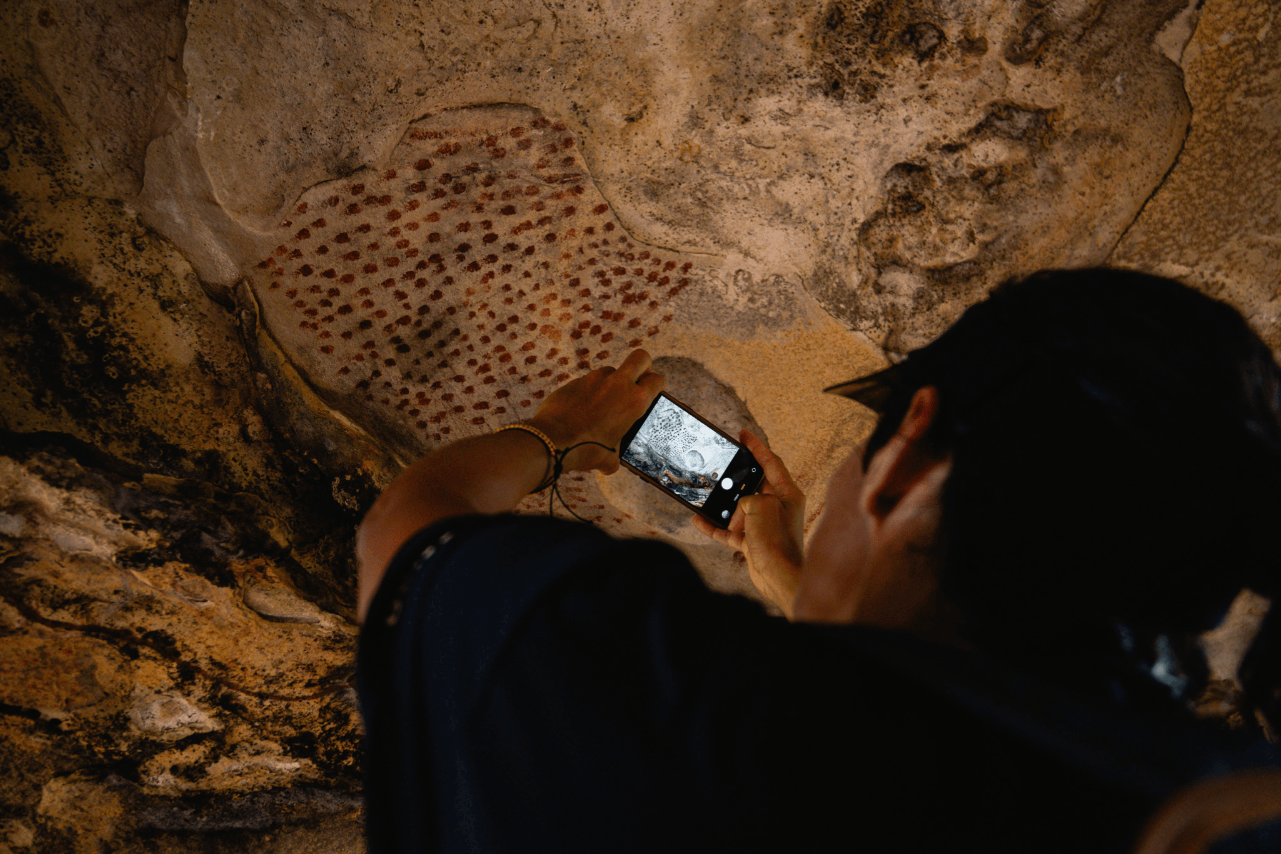 Viajante fotografando pinturas rupestres em sítio arqueológico na Trilha Caminhos da Ibiapaba, Nordeste do Brasil
