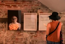 Visitante observando exposição com retrato de Gabriel García Márquez e manuscritos emoldurados em parede de tijolos na Colômbia