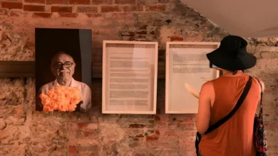 Visitante observando exposição com retrato de Gabriel García Márquez e manuscritos emoldurados em parede de tijolos na Colômbia