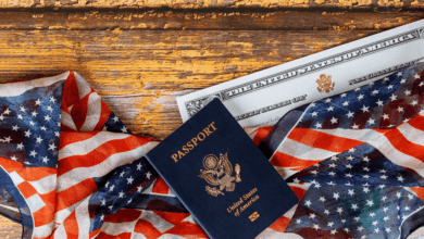 Close em visto americano estampado no passaporte com bandeira dos Estados Unidos ao fundo.