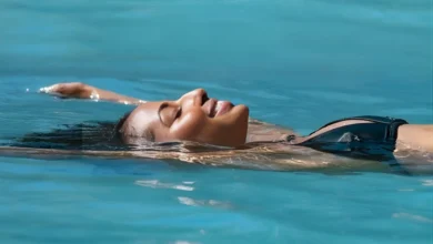 Mulher de olhos fechados flutuando relaxada em piscina de água termal azul-turquesa