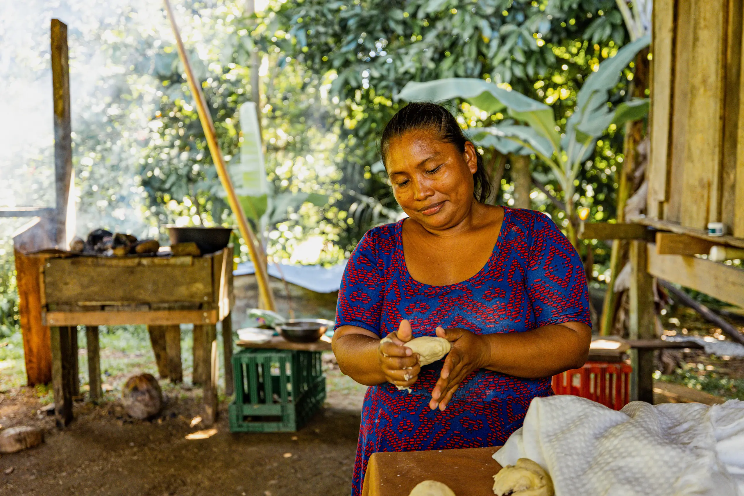 Mulher indígena Ngäbe-Buglé preparando alimento artesanalmente em comunidade de Bocas del Toro no Panamá com vegetação tropical ao fundo
