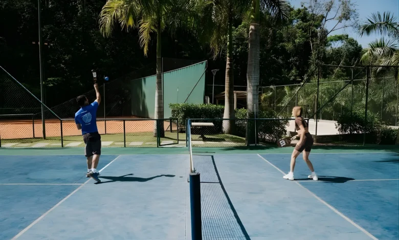 Dois jogadores praticando pickleball em quadra do Rituaali Clínica & Spa rodeada por palmeiras e vegetação tropical