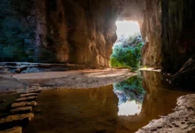 Interior da Gruta do Janelão no Peruaçu com abertura em arco iluminada pela luz natural refletida em lago interno