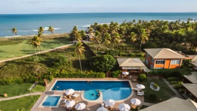 Vista aérea do Hotel Boutique e Spa Ponta de Inhambupe com piscina, palmeiras e o mar ao fundo em dia ensolarado