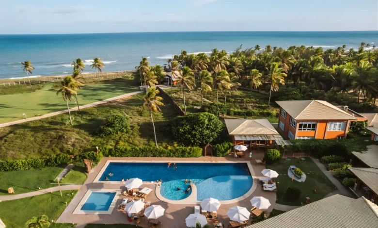 Vista aérea do Hotel Boutique e Spa Ponta de Inhambupe com piscina, palmeiras e o mar ao fundo em dia ensolarado