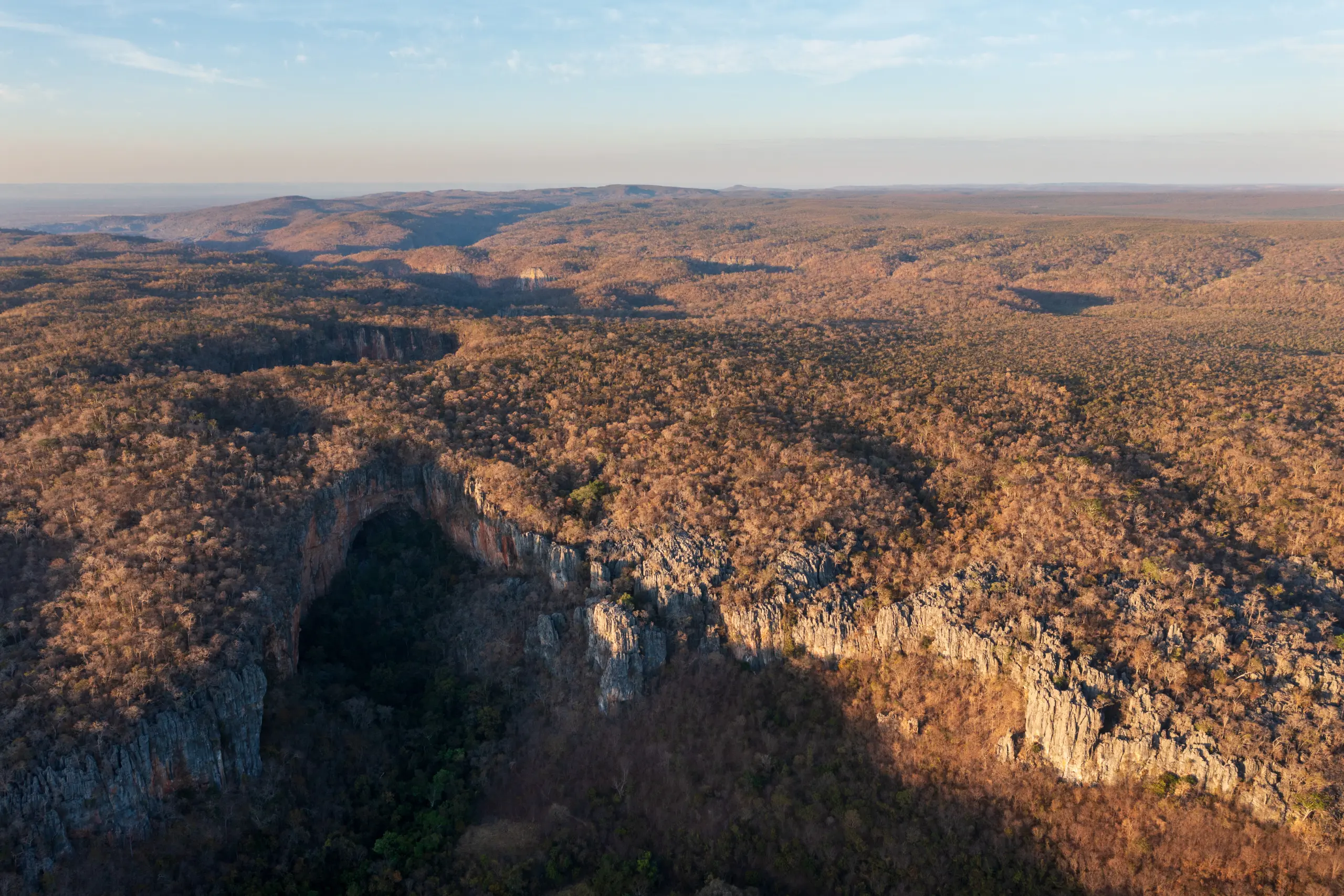 Vista aérea do Cânion do Peruaçu com abertura de caverna em paredão rochoso cercado por vegetação de cerrado em Minas Gerais