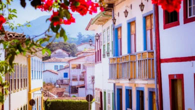 Rua histórica de Ouro Preto com casarões coloniais coloridos flores vermelhas e montanhas ao fundo