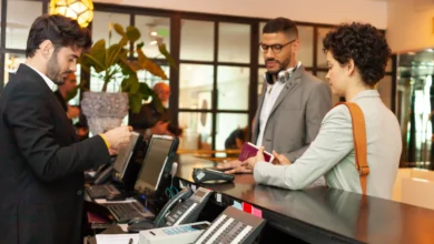 Recepcionista de hotel fazendo check-in de casal com passaporte em balcão de recepção iluminado