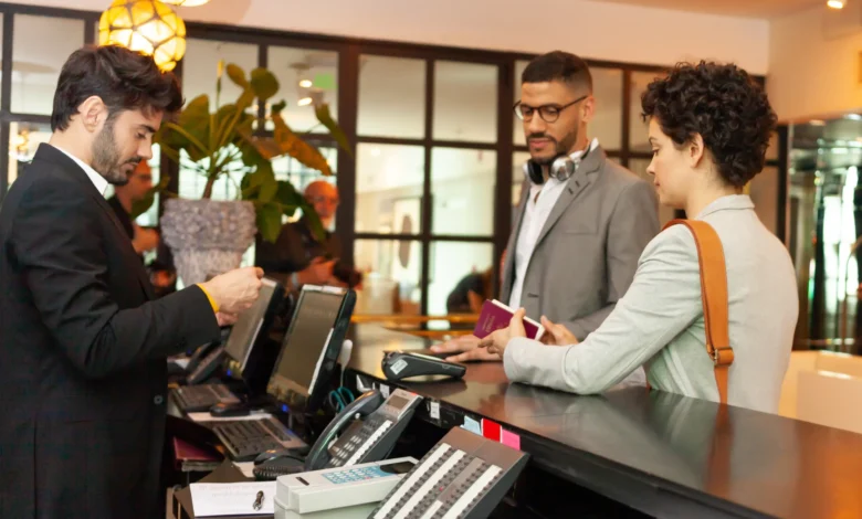 Recepcionista de hotel fazendo check-in de casal com passaporte em balcão de recepção iluminado
