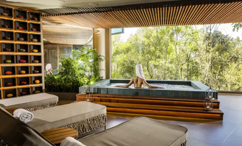 Área de hidroterapia do spa do Bendito Cacao Resort e Spa com mulher relaxando em banheira com vista para vegetação da Serra da Mantiqueira