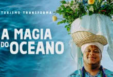 Homem negro com trajes afro-brasileiros em azul e branco ao lado do texto "A Magia do Oceano" — série Turismo Transforma da Embratur